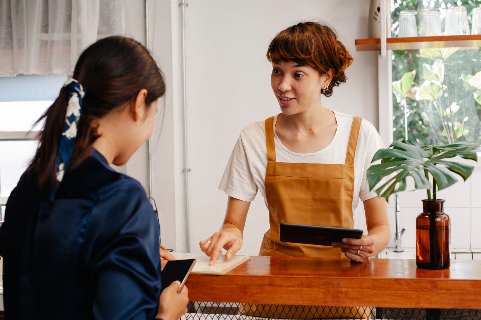 Profissional de um café conversando com uma pessoa junto ao balcão